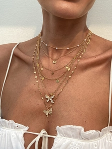 Detailed layered gold necklace set with butterfly charms and star accents on skin