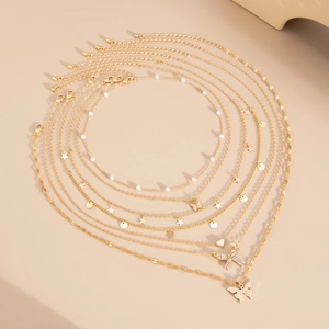 Flat lay of 7-piece gold butterfly necklace set with faux pearls and star charms