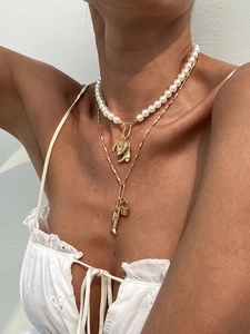 Detail of layered gold necklace featuring pearls, heart, and western boot charms