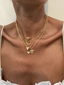 Close-up of layered gold necklace set featuring heart pendants and a snake chain on a model