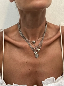 Close-up of layered silver heart pendants and snake chains on a female neck