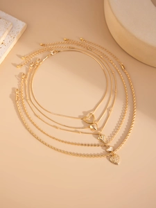 Close-up of gold layered heart necklace with diverse chain textures and elegant pendants