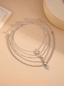 Detailed view of 5-piece silver heart layered necklaces on elegant stone props