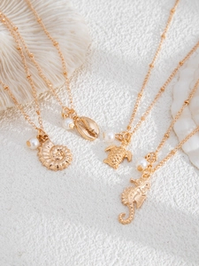 Detail of four gold ocean-themed necklaces with shell, turtle, and seahorse charms