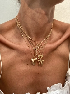 Close-up of layered gold butterfly pendant necklaces featuring multiple chain styles