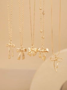 Detail view of five different gold bow-shaped pendant necklaces with varied chain styles