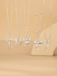 Detailed view of assorted silver bow necklaces on elegant minimalist displays
