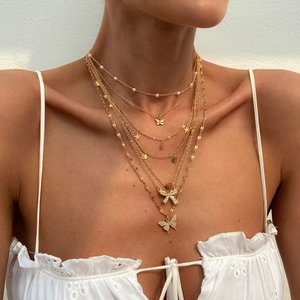 Multilayer gold necklace featuring butterfly and pearl pendants in a layered bohemian style