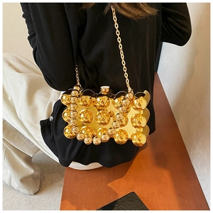 Detail of gold metal spherical acrylic evening bag with delicate chain shoulder strap