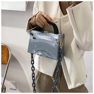 Detail of marble pattern acrylic box bag with chunky blue chain strap and top handle