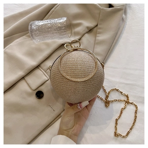 Détail d'un sac de soirée sphérique doré avec finition pailletée et poignée en métal
