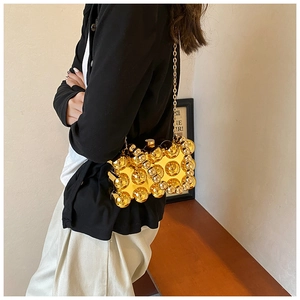 Close-up of a gold spherical studded acrylic evening bag with a slender metal chain