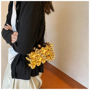 Detail of creative crossbody bag with gold metallic spheres and a sleek chain strap