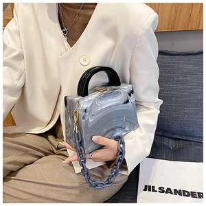 Detail of acrylic handbag with marble pattern, featuring thick chain and gold hardware