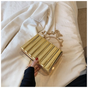 Macro shot of gold metallic wave-textured clutch with round handle and chain strap