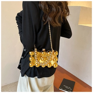 Detail of metallic gold acrylic clutch with 3D beaded texture and gold chain strap