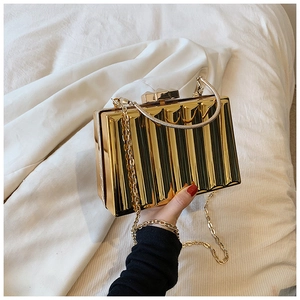 Macro view of golden pleated hard-shell evening clutch with circular handle and chain