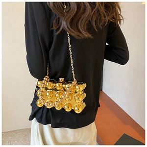 Detailed view of a gold metallic evening clutch bag with spherical 3D texture and chain