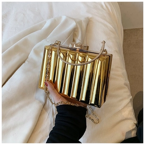 Close-up of golden metallic clutch bag featuring vertical texture and elegant top handle