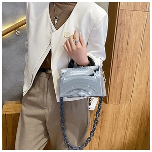 Detail view of marble patterned acrylic handbag with black handle and resin chain strap