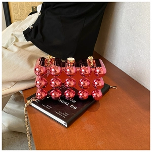 Macro shot of metallic pink acrylic clutch bag featuring 3D bubble texture and gold chain