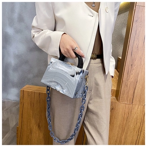 Detail of marble pattern resin square handbag with black handle and blue chain strap