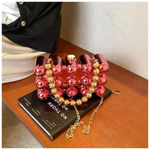 Close-up of pink mirror egg-shaped clutch bag with golden beaded handle and chain