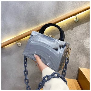 Detail of marble pattern square clutch bag with acrylic chain and round handle