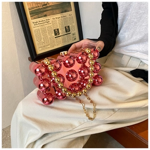 Detail of pink spherical acrylic evening bag with gold beaded handle and metal chain