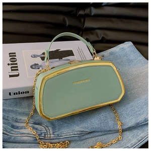 Dettaglio borsa a scatola verde menta con cornice dorata su jeans e rivista di moda