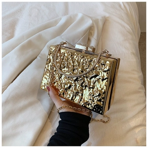 Detail of gold liquid metal texture evening clutch bag with elegant snake chain handle
