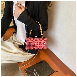 Detail of pink acrylic evening clutch featuring bubble texture and golden bead handle