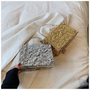 Macro shot of gold and silver clutch bags with hammered metal texture and ring handles