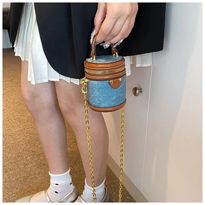 Mini denim cylinder bucket bag with brown leather trim and gold chain strap detail