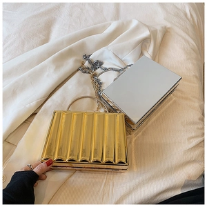 Close-up of gold wavy texture and silver mirror acrylic clutch bags with chain handles