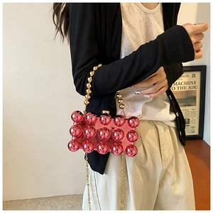 Detail of red acrylic box bag featuring 3D spherical texture and golden chain strap