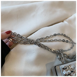 Detailed macro view of a silver liquid metal texture acrylic box bag with chunky chain