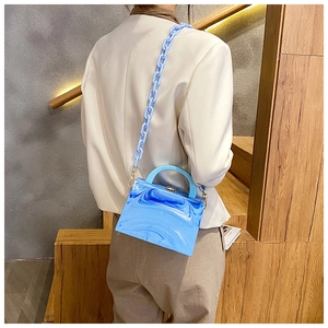 Detail of blue marble acrylic box bag featuring thick plastic chain on person