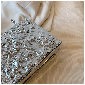 Detail of silver rectangle evening clutch with hammered metal texture and ball clasp