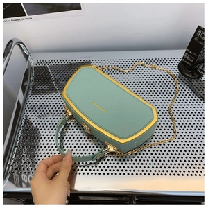 Dettaglio borsa a scatola verde menta con cornice dorata e tracolla a catena su display