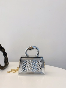 Detail of silver evening clutch bag with V-shaped embossing and gold chain strap