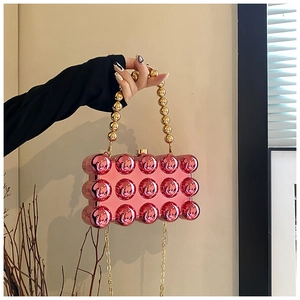 Macro detail of metallic pink acrylic clutch bag featuring 3D spherical relief textures