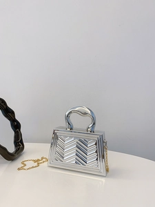 Close-up of metallic silver handbag with textured V-pattern and curved metal handle