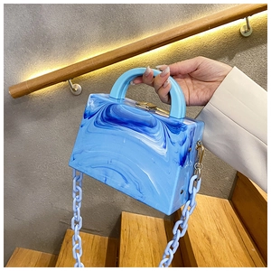 Detail of blue marble acrylic handbag with thick chain strap and gold metal clasp lock