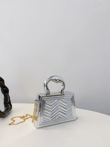 Silver trapezoid handbag featuring textured V-shaped patterns and chunky metallic handle