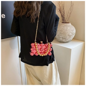 Close-up of pink acrylic box bag with spherical accents and gold chain strap