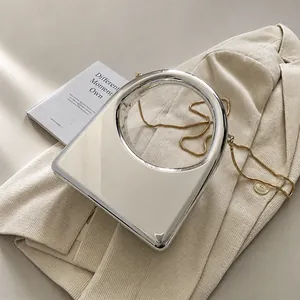 Detalle de bolso acrílico plateado con asa circular grande y correa de cadena dorada