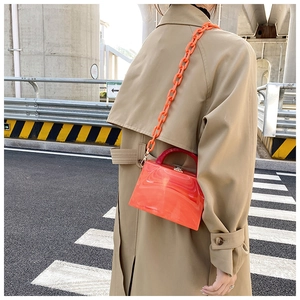 Macro detail of coral acrylic handbag with thick resin chain strap and marble texture