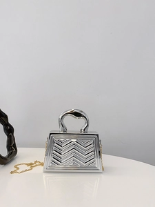 Macro shot of silver metallic trapezoid bag with embossed wavy texture and gold chain strap