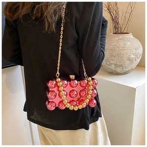 Detail of pink acrylic box bag featuring 3D spherical studs and gold chain strap